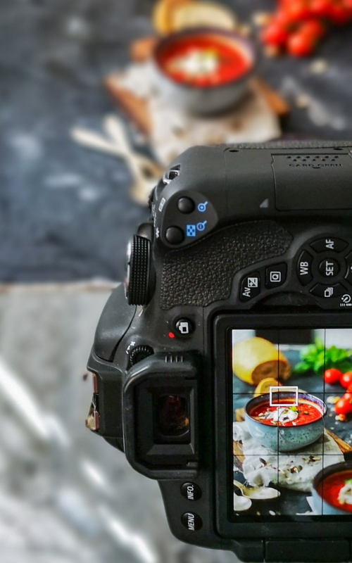 Camera on a tripod is capturing a styled food scene.